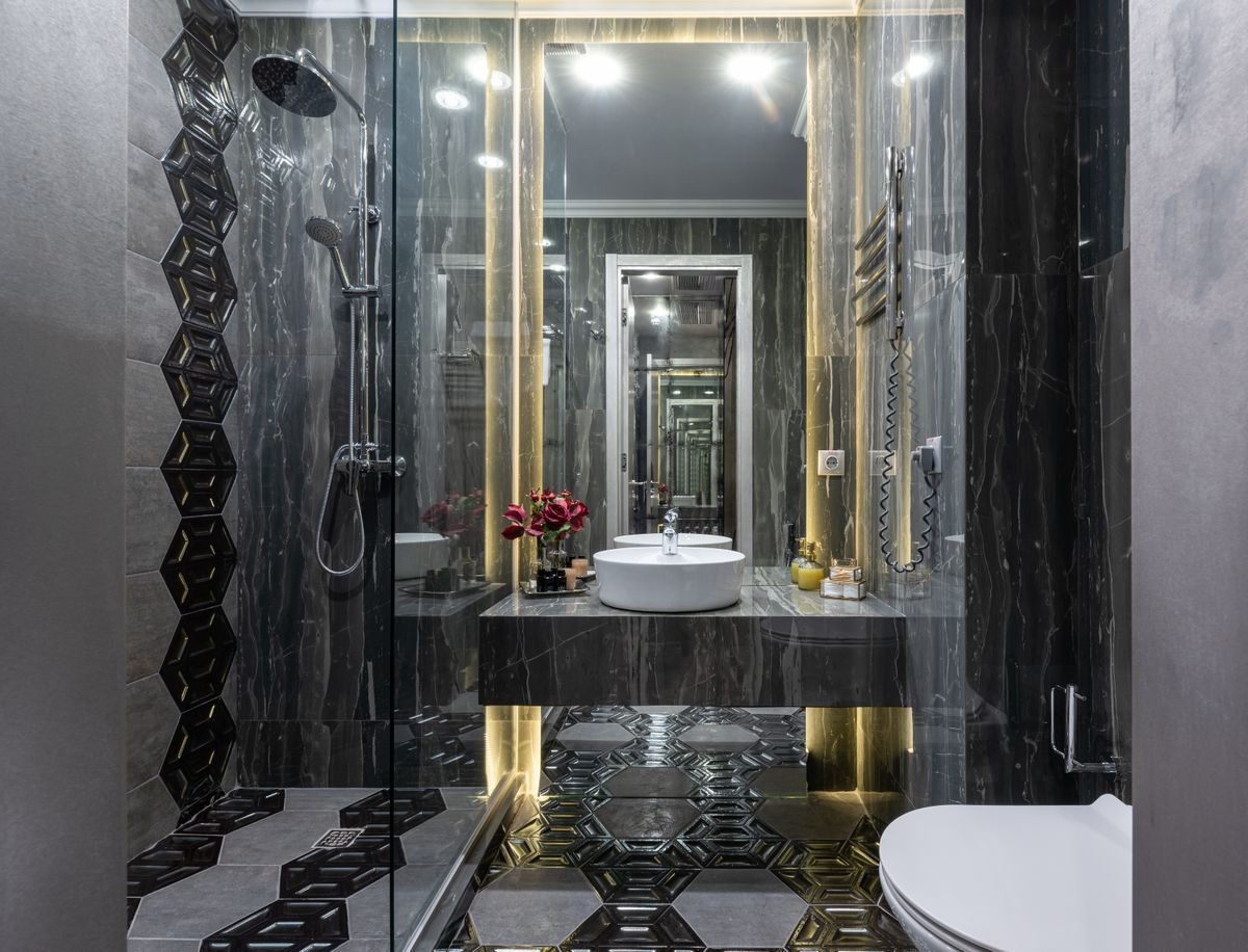 Baño con revestimiento porcelánico oscuro y suelo de mosaico